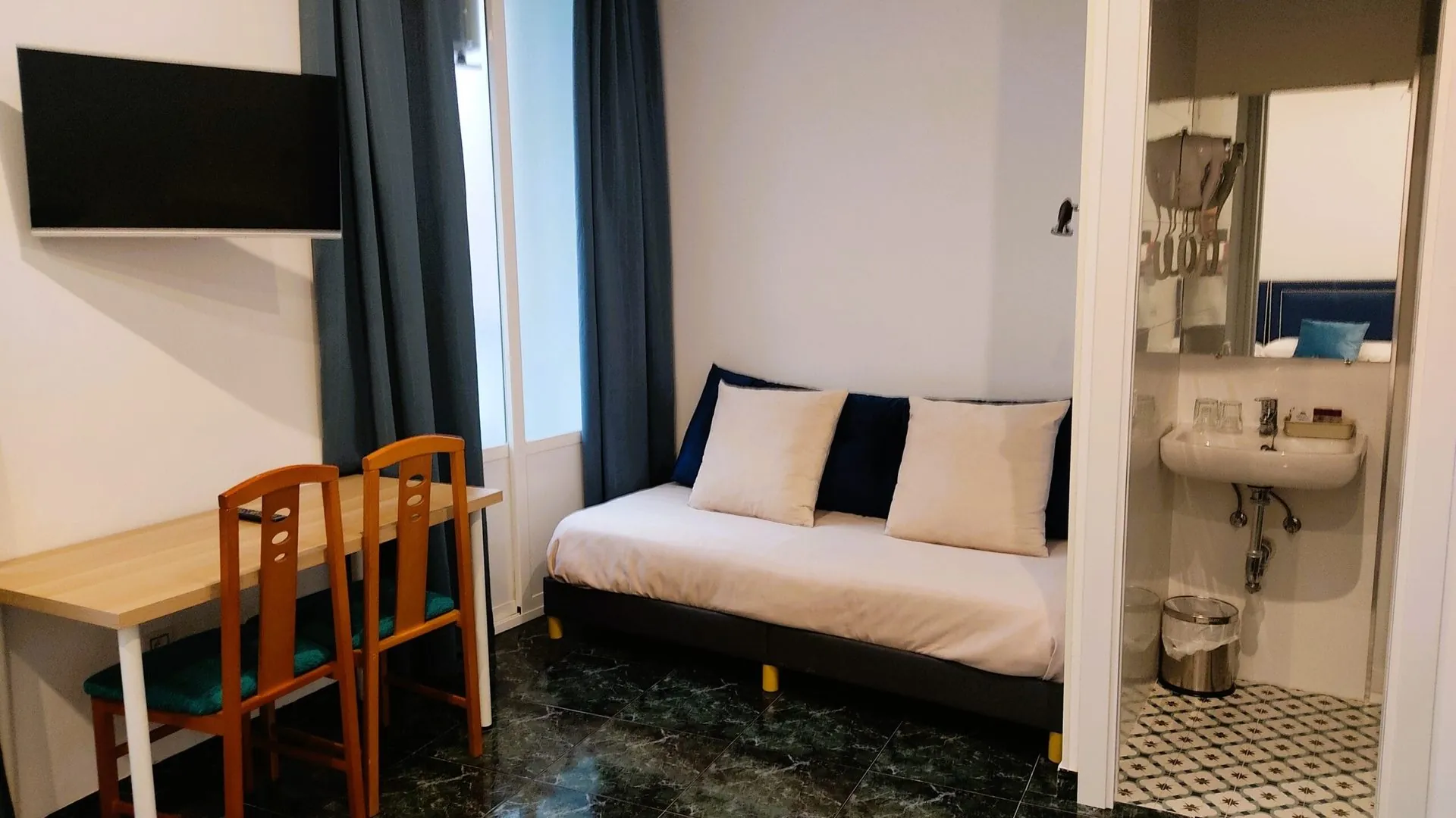 Habitación con sofá, escritorio, televisión y baño en el Hostal Bruña